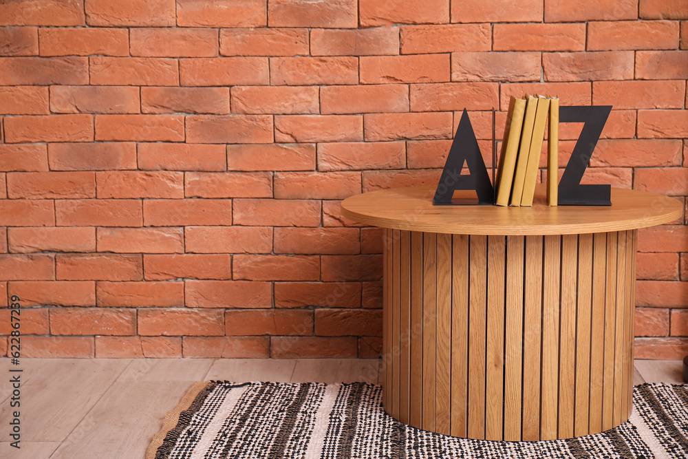 Wooden coffee table with books near brown brick wall