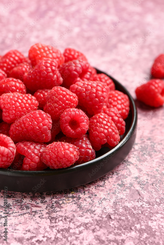 Tray with fresh raspberries on purple background