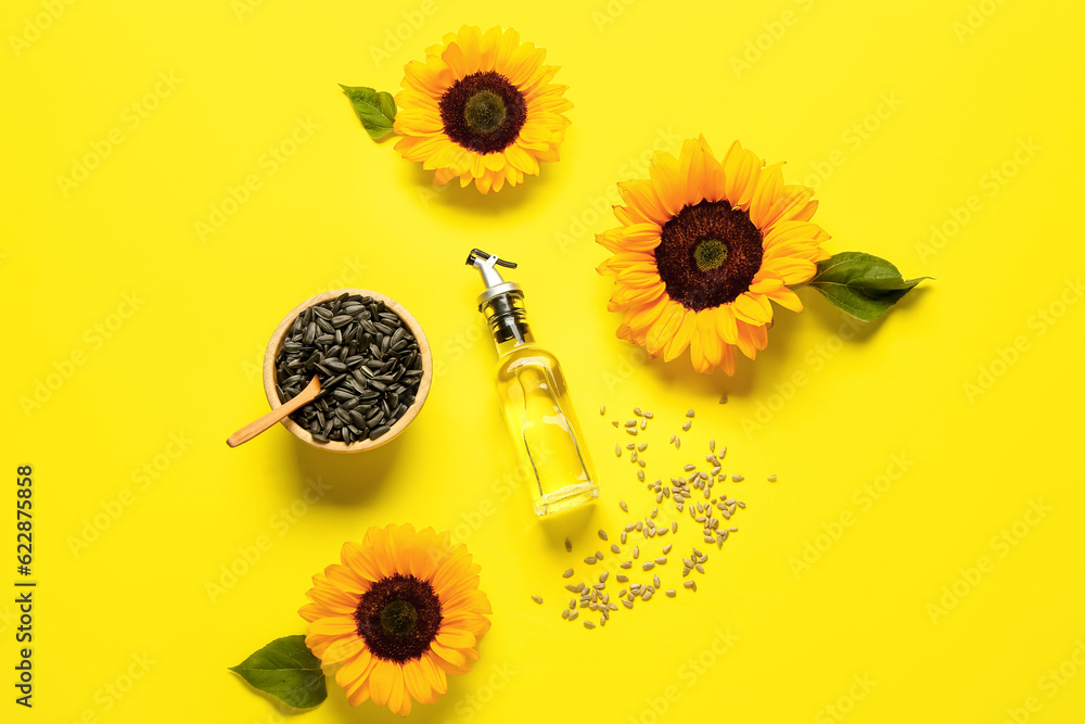 Sunflowers, seeds and bottle of oil on yellow background