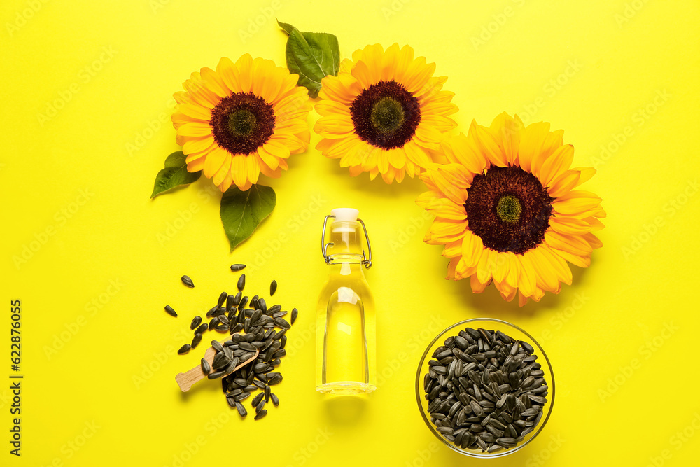 Sunflowers, seeds and bottle of oil on yellow background