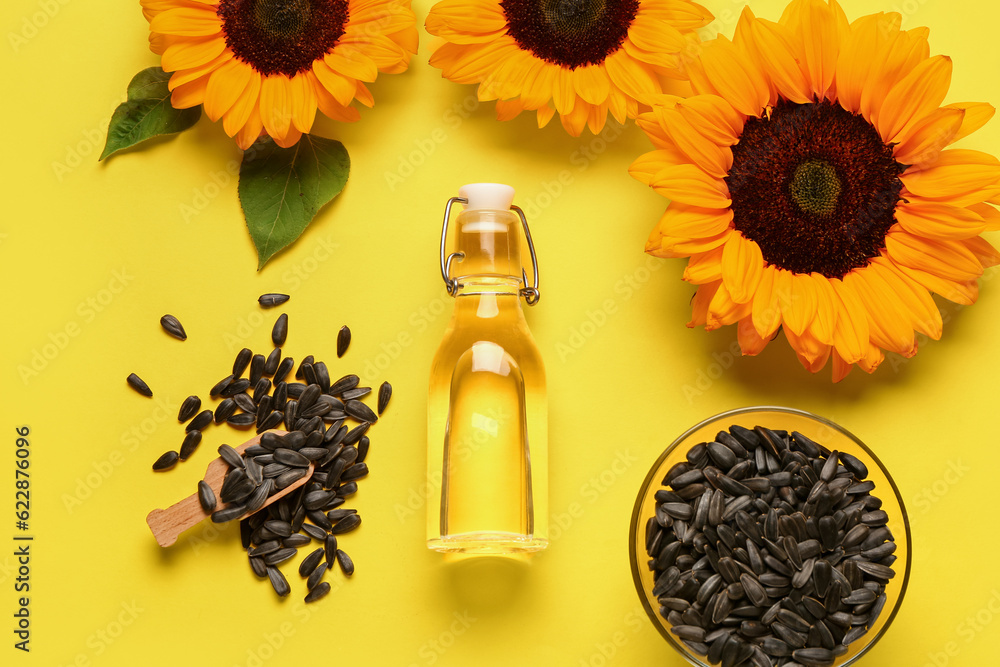 Sunflowers, seeds and bottle of oil on yellow background