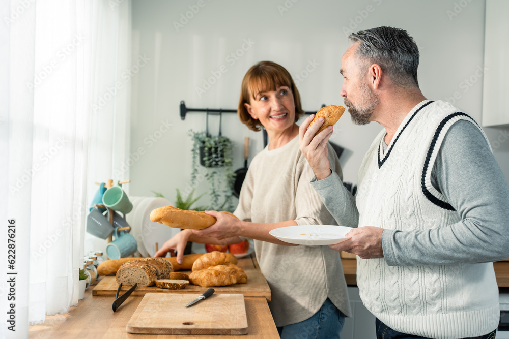 Caucasian senior elderly couple spend time together in kitchen at home. 