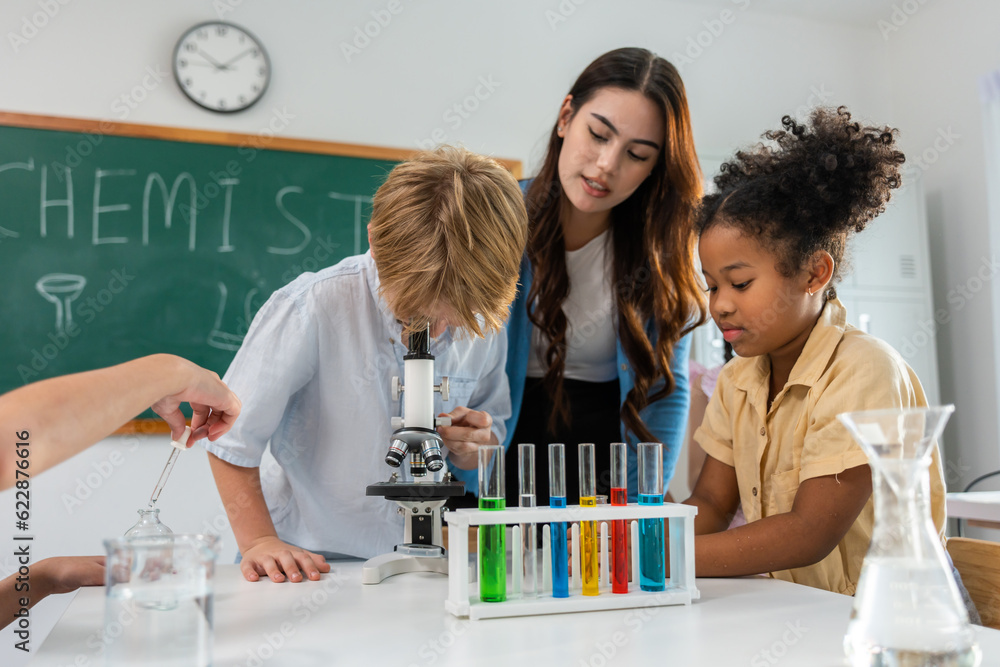 Adorable student learn with teacher in classroom at elementary school. 