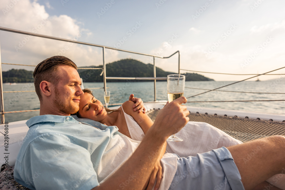 Caucasian young couple drinking champagne while having party in yacht. 