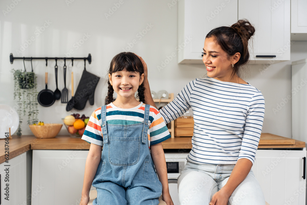 Portrait of Caucasian mother and daughter look at camera in kitchen. 