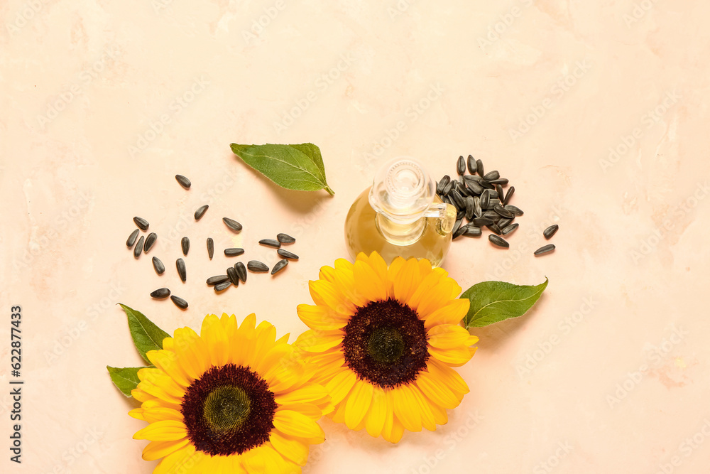 Sunflowers, seeds and decanter of oil on beige background