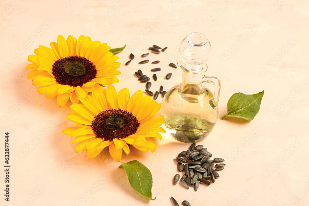 Sunflowers, seeds and decanter of oil on beige background