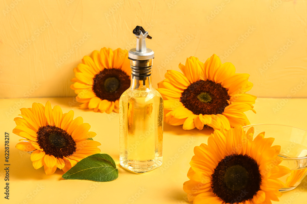 Sunflowers and bottle of oil on yellow background