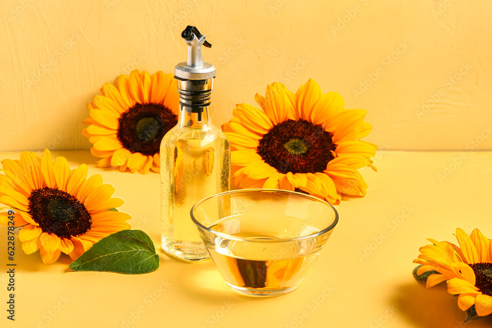 Sunflowers, bottle and bowl of oil on yellow background