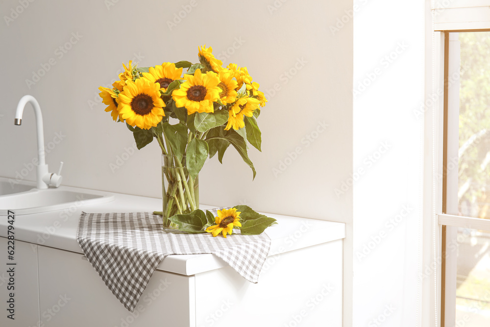 Vase with beautiful sunflowers on white kitchen counter