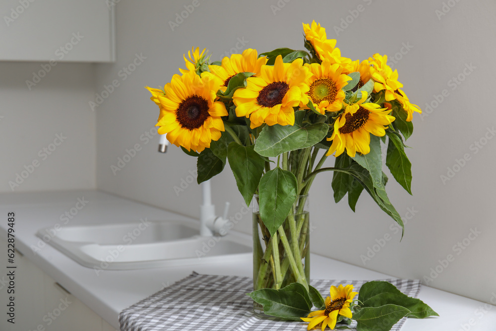 Vase with beautiful sunflowers on white kitchen counter