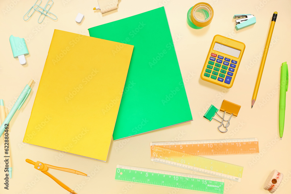 Notebooks with different stationery on pale yellow background