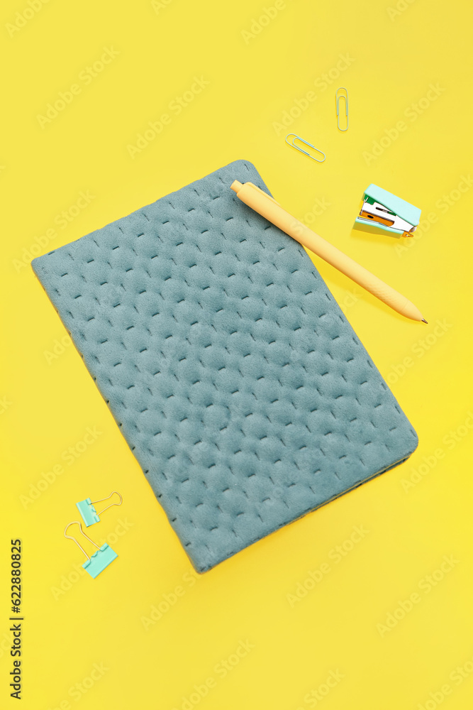 Notebook with stationery on yellow background