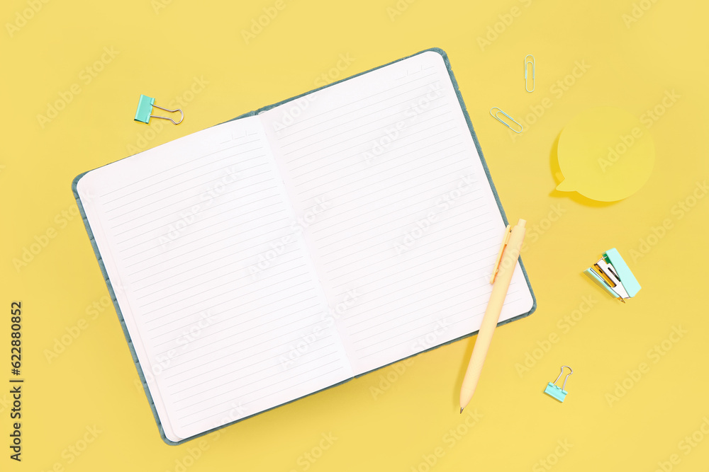 Blank notebook with stationery on yellow background