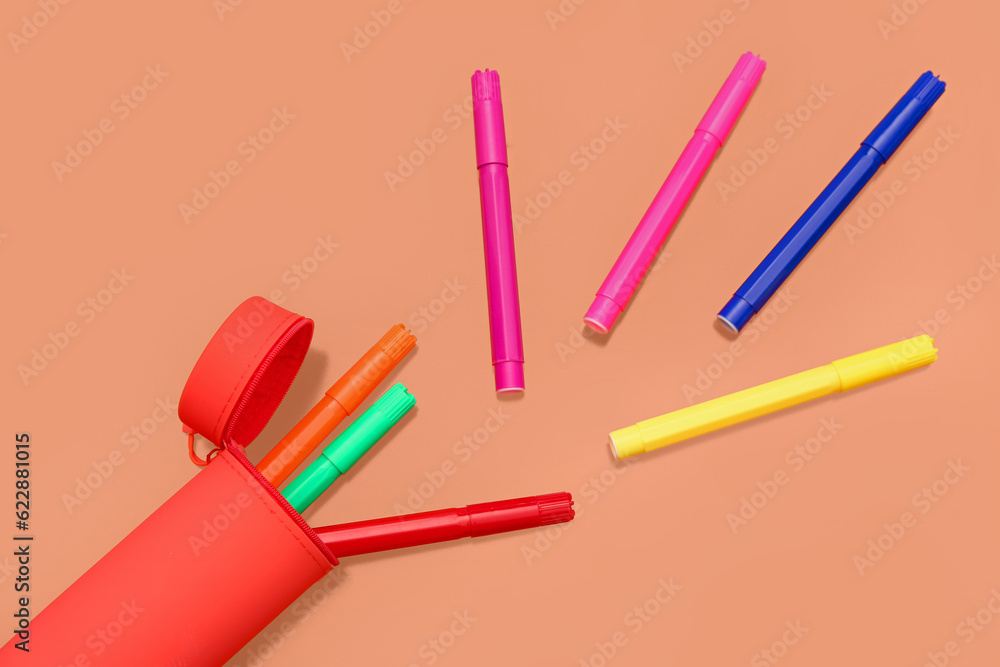 Different colorful markers in case on orange background