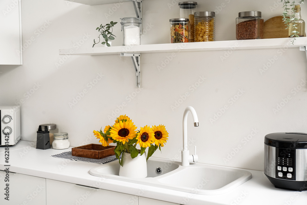 Vase with beautiful sunflowers in kitchen sink