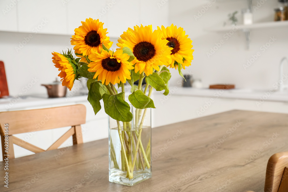 Vase with beautiful sunflowers on wooden table in kitchen, closeup