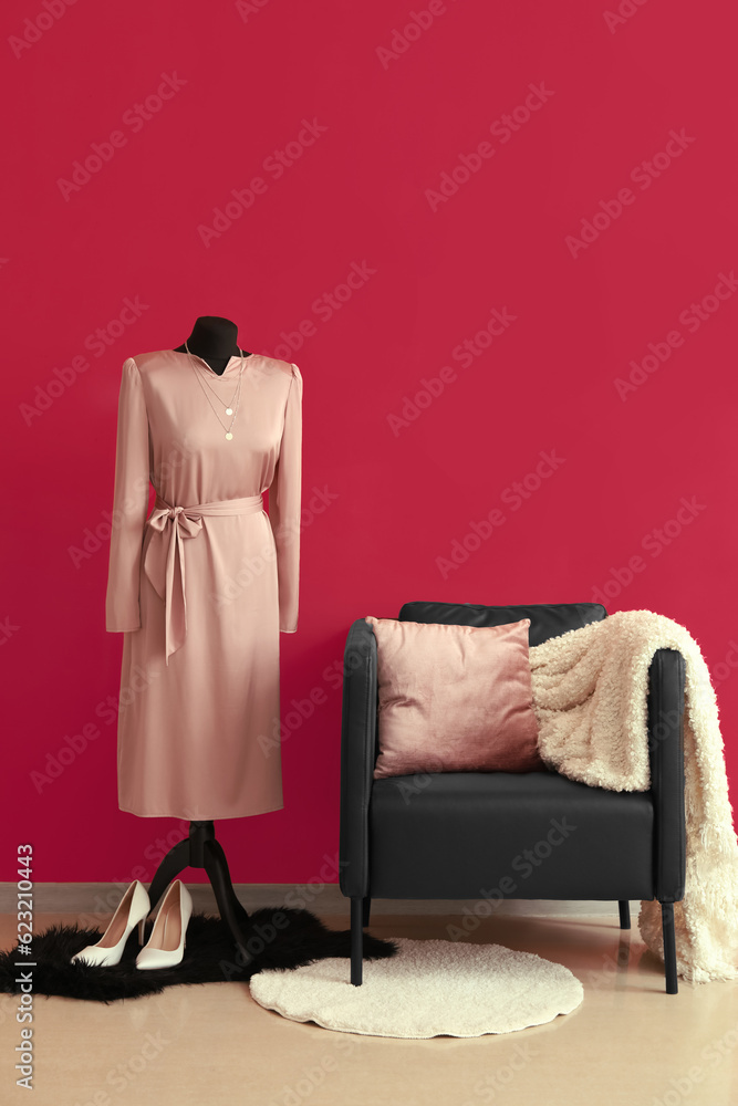 Black armchair and mannequin near pink wall in room