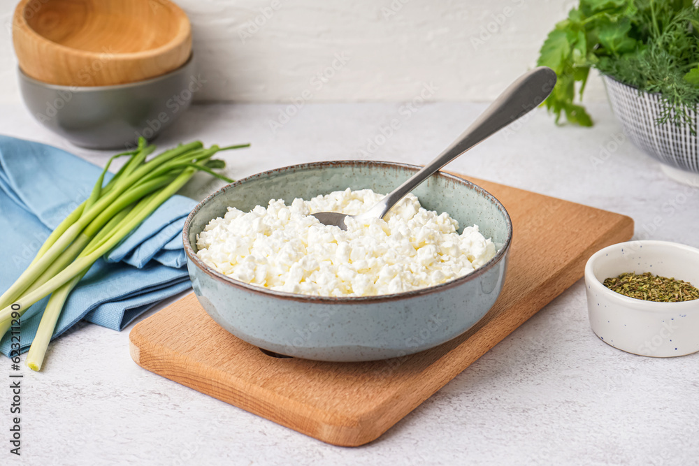 Bowl with tasty cottage cheese on light background