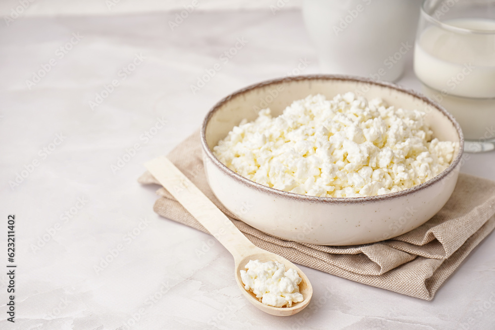 Bowl with tasty cottage cheese on light background