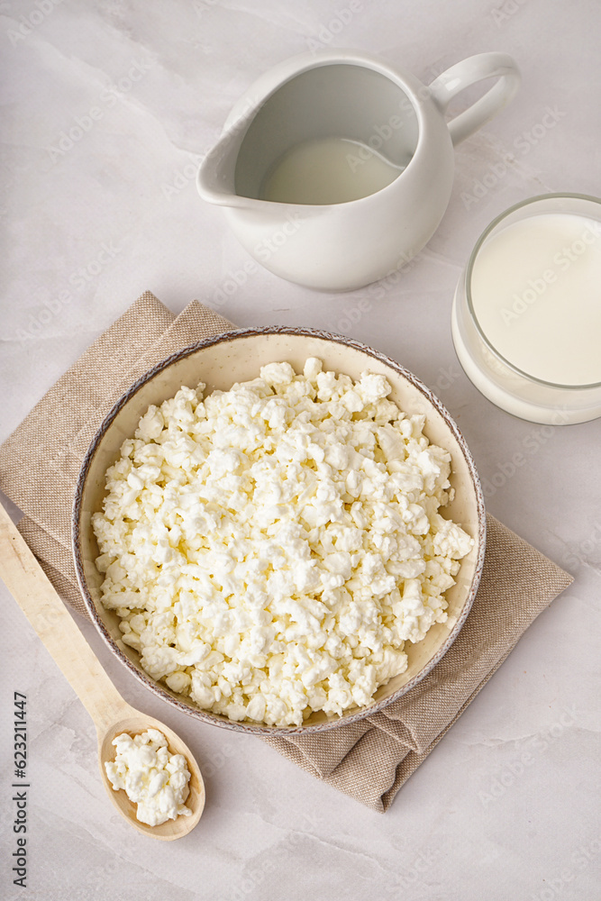 Bowl with tasty cottage cheese on light background