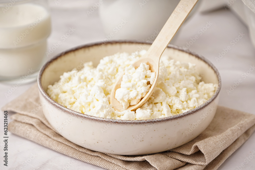 Bowl with tasty cottage cheese on light background