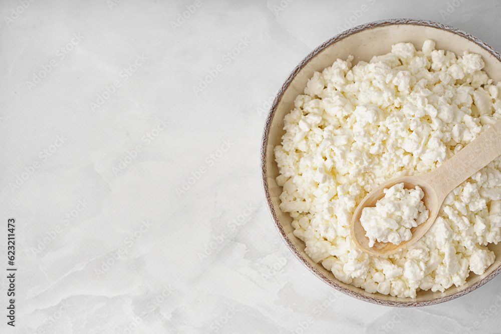 Bowl with tasty cottage cheese on light background