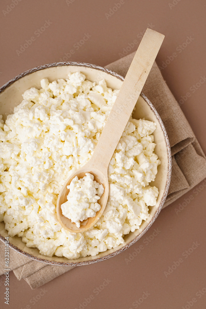 Bowl with tasty cottage cheese on beige background