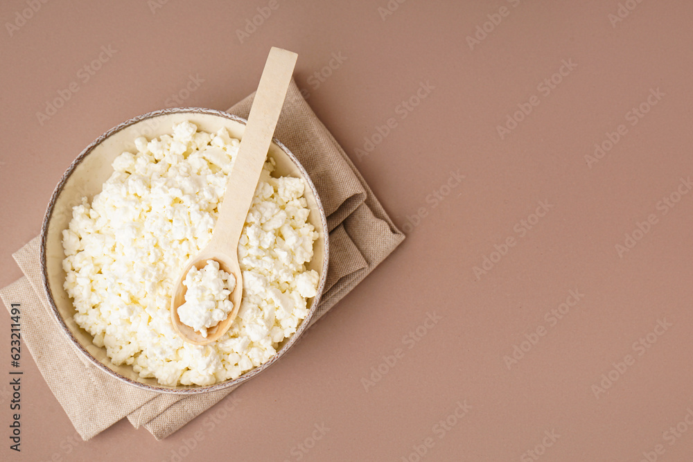 Bowl with tasty cottage cheese on beige background