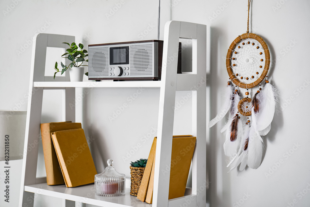 Dream catcher hanging on light wall near shelving unit