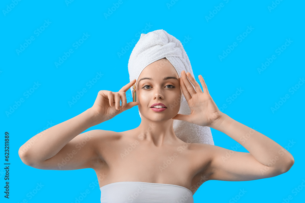 Beautiful young woman with ampule on blue background. Skin care concept