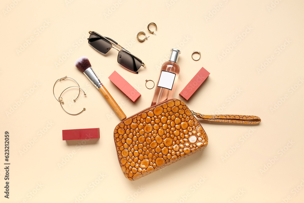 Cosmetic bag with sunglasses, makeup products and accessories on pale orange background