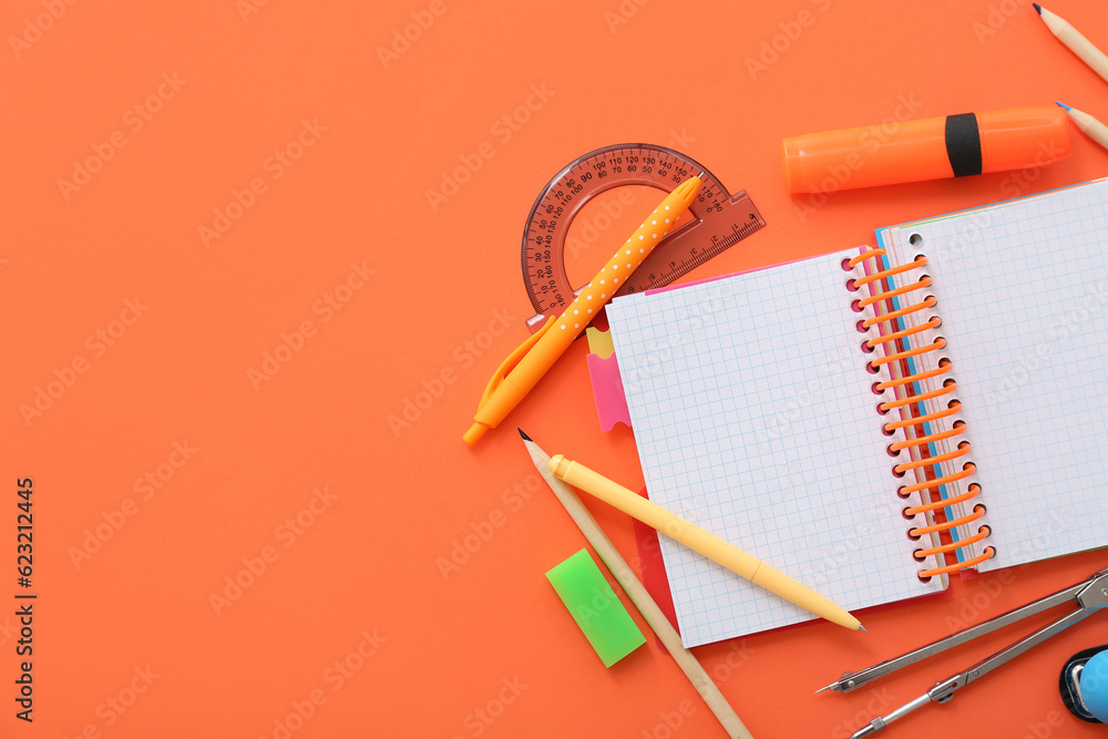 Blank notebook with different stationery on orange background