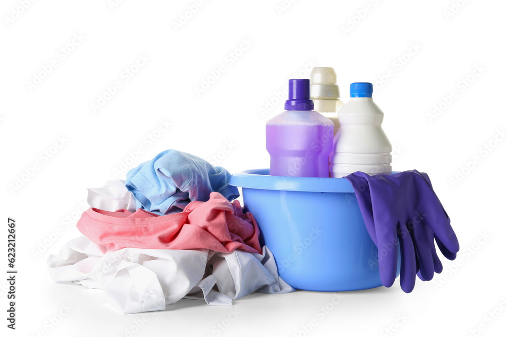 Pile of dirty clothes with bottles of laundry detergent and rubber gloves in plastic basin isolated 