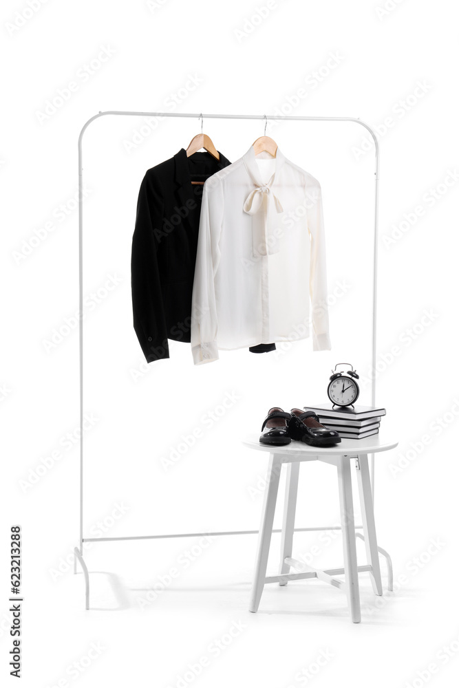 Rack with stylish school uniform, chair, books, alarm clock and shoes on white background