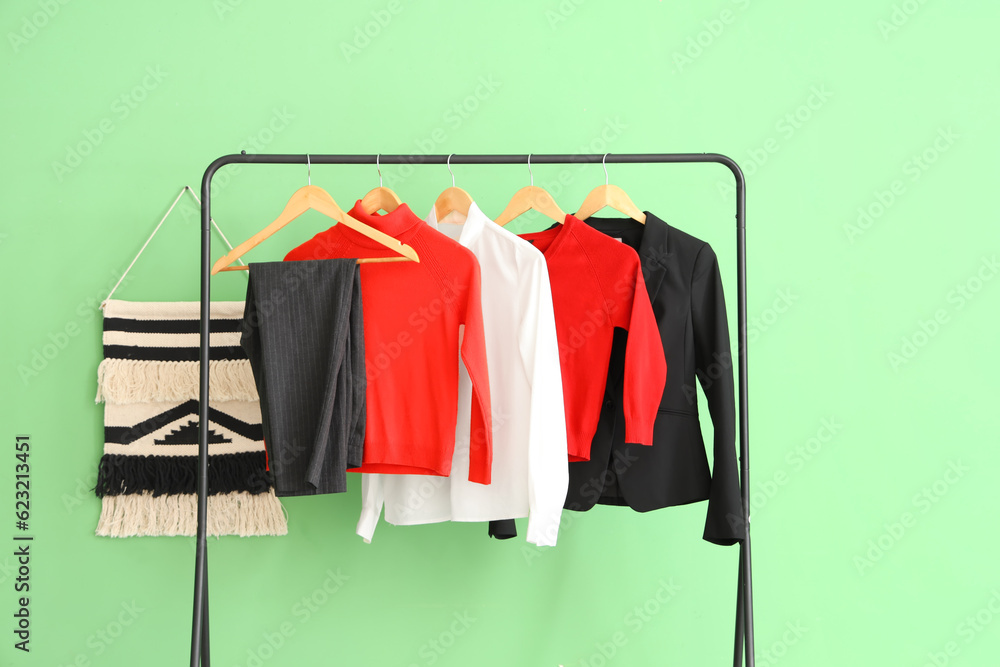 Stylish school uniform hanging on rack near green wall in room