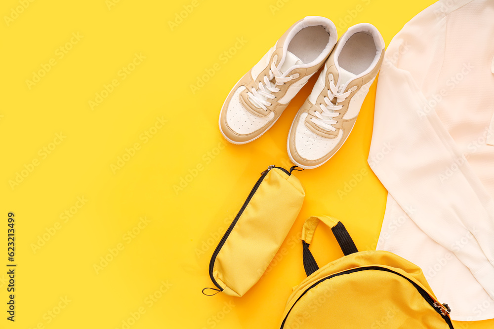 Composition with stylish school uniform, backpack, sneakers and pencil case on orange background