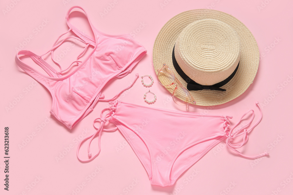 Stylish swimsuit, hat, sunglasses and accessories on pink background