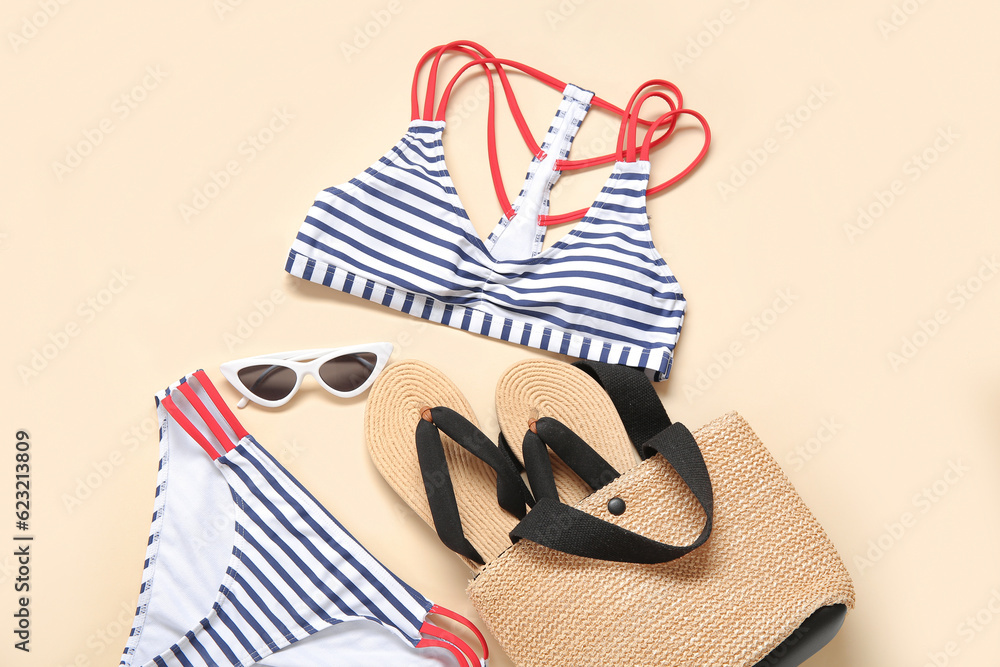 Stylish swimsuit, bag, flip-flops and sunglasses on color background