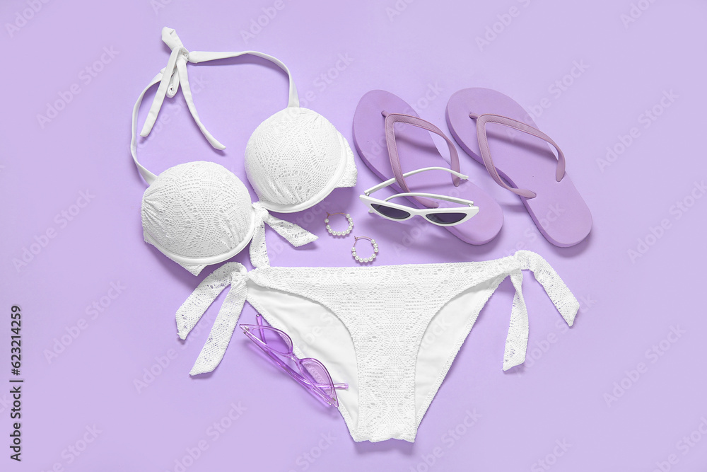 Stylish swimsuit, flip-flops, sunglasses and earrings on lilac background