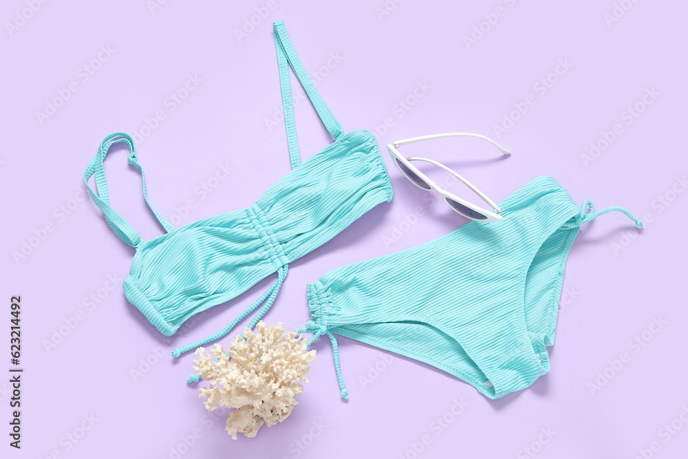 Stylish swimsuit, sunglasses and coral on color background