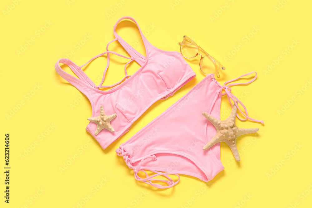 Stylish swimsuit and starfishes on yellow background