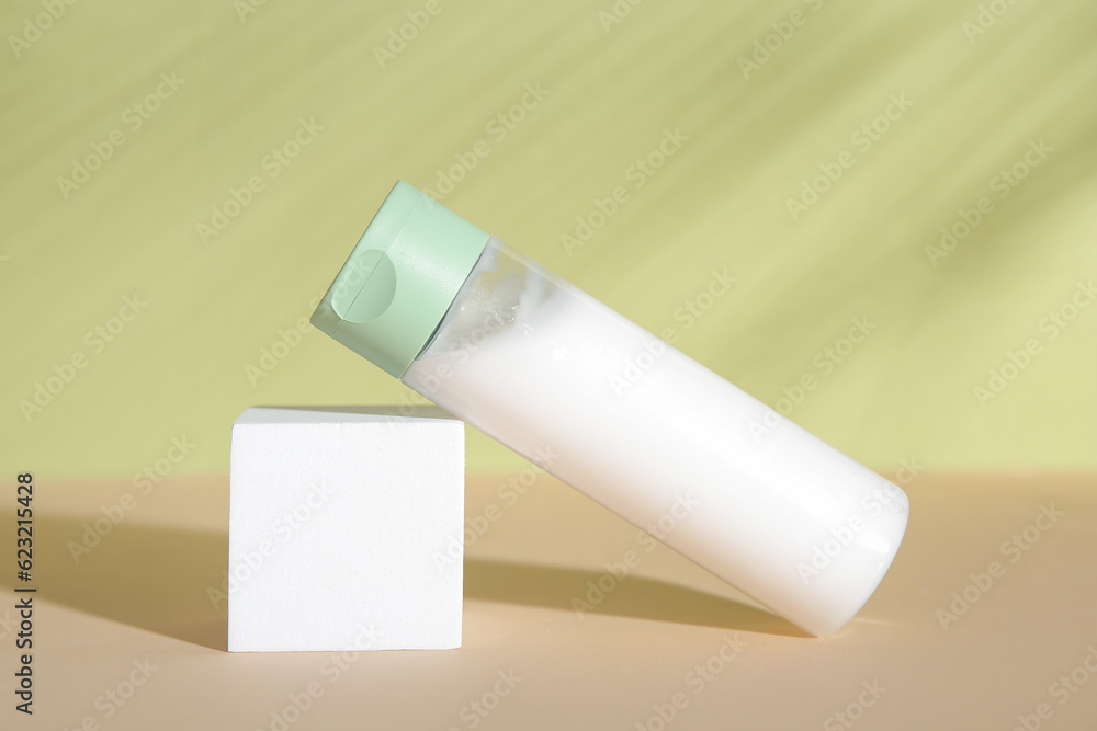 Bottle of cosmetic product, plaster podium and palm leaf shadow on green background