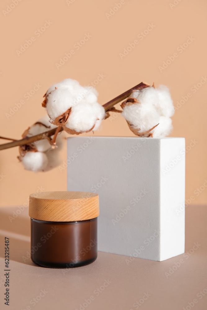 Jar of cosmetic product, plaster podium and cotton branch on color background