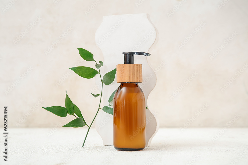 Bottle of cosmetic product, plaster decor and plant branch on light background