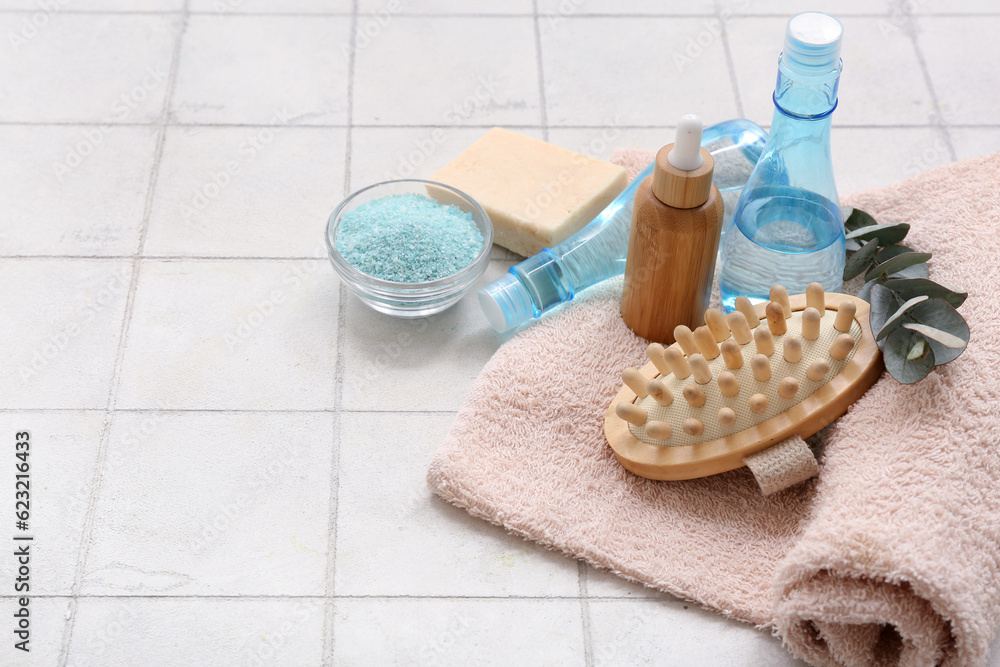 Set of bath supplies and cosmetic products on light tile background