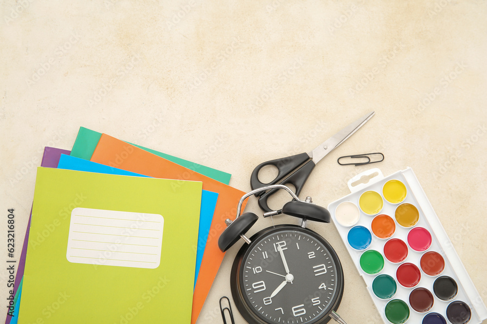 Alarm clock with different stationery on beige background