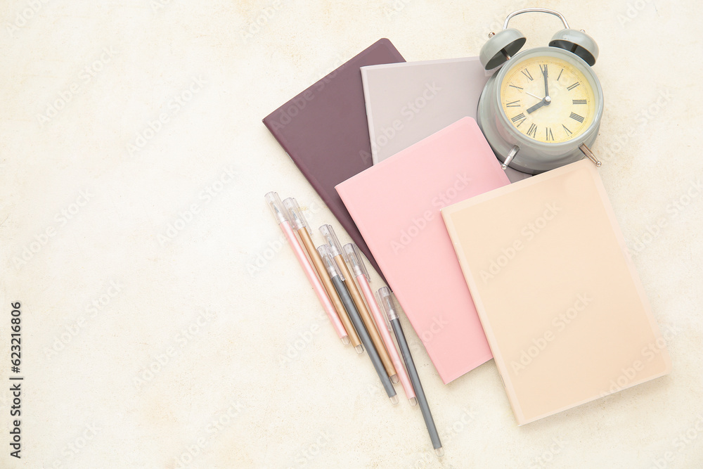 Alarm clock with different stationery on beige background