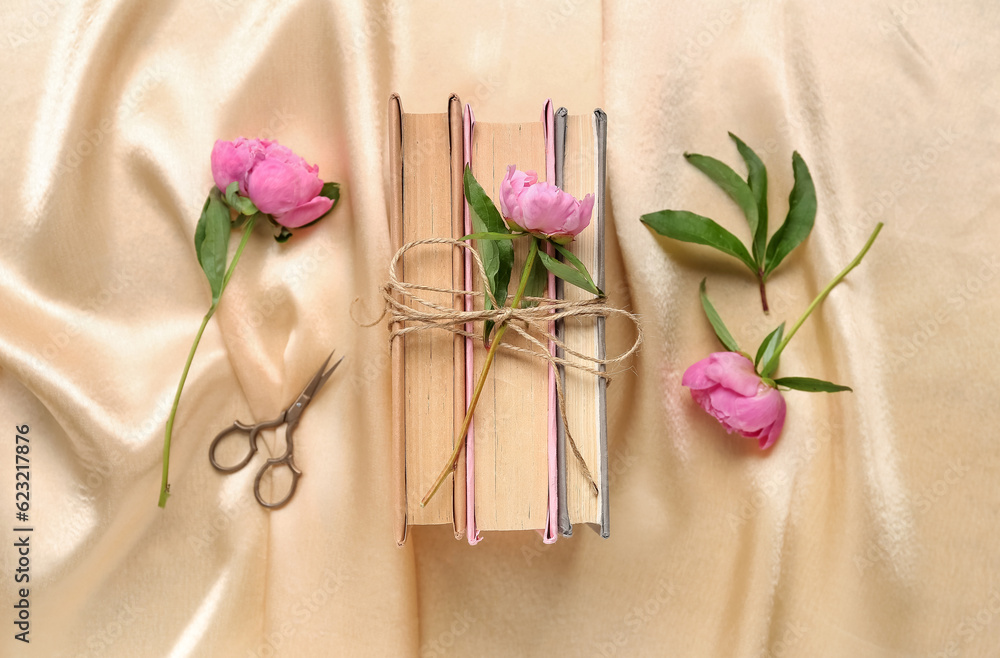 Composition with books, scissors and beautiful peony flowers on fabric background