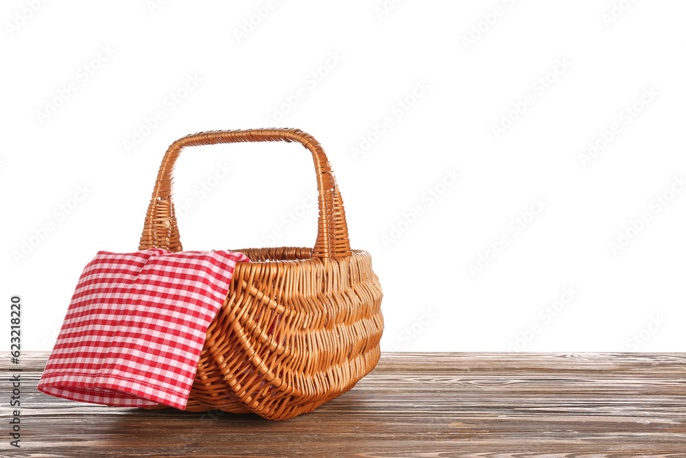 Wicker picnic basket with napkin on wooden table against white background